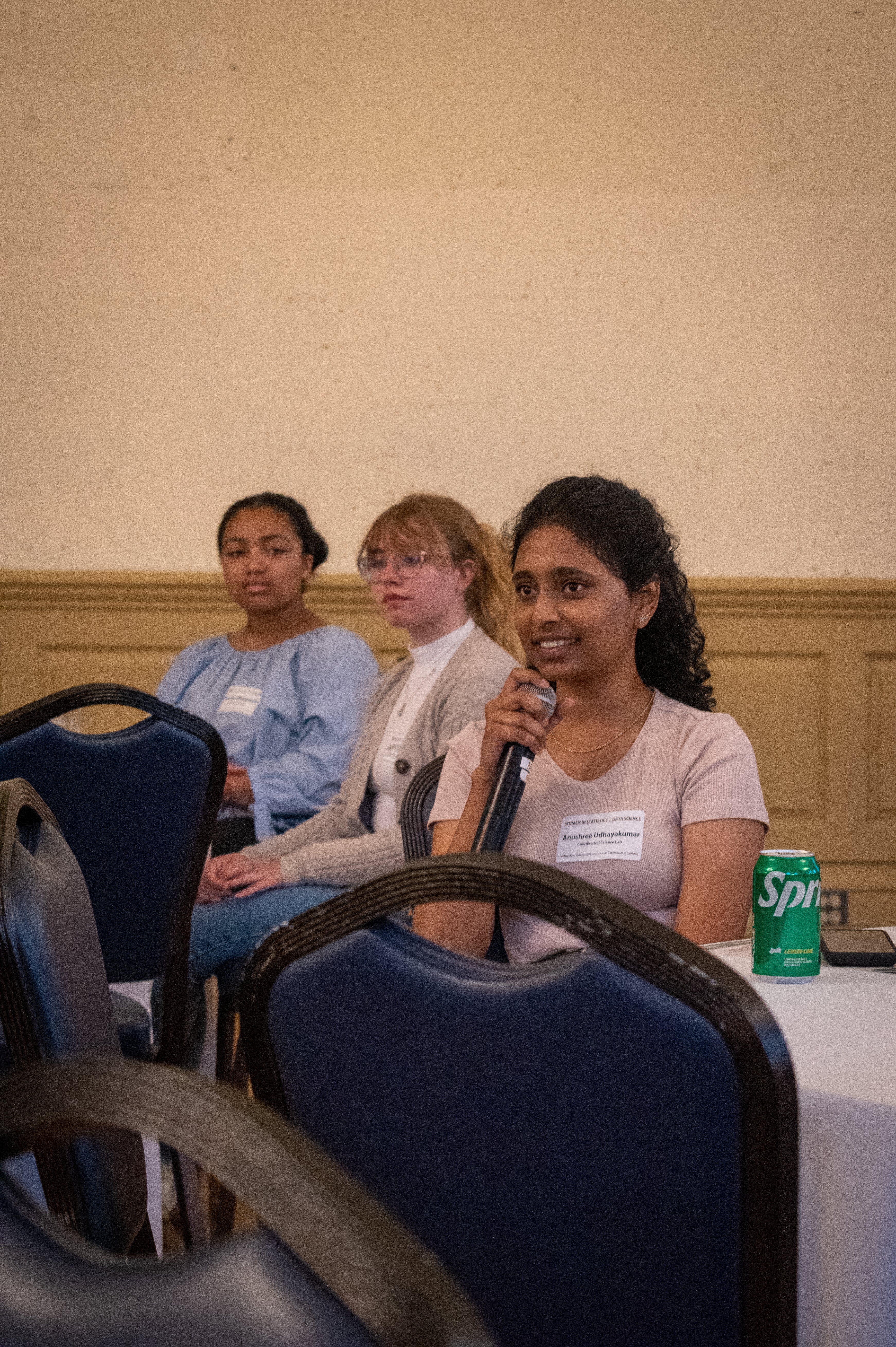 Student holds microphone as she asks question 