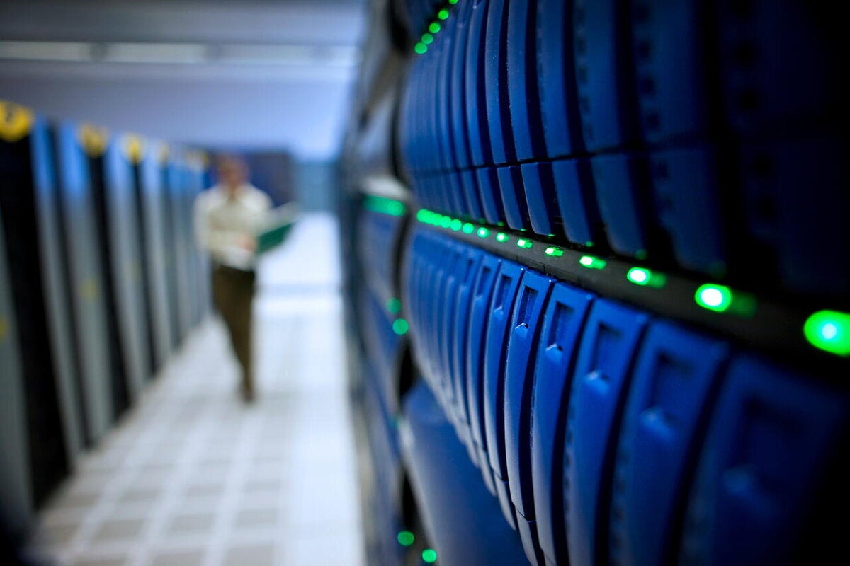 Man walking down row of servers