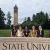 Undergraduate students standing behind Iowa State University sign