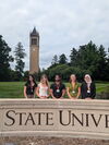 Undergraduate students standing behind Iowa State University sign